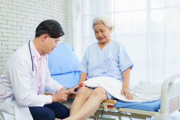 Obraz premium Doctor checking elderly patient’s knee for osteoarthritis.