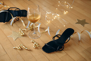 Party or after party background birthday wedding Christmas new year  black high-heeled shoes surrounded by festive decorations and a glass of wine, celebratory atmosphere