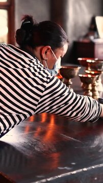 Woman in striped long sleeve shirt cleaning candle stand indoors