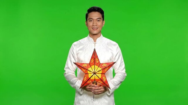 Smiling Man in Embroidered White Shirt Holding Decorative Star Lantern on Isolated Green Screen Background Celebration of Asian