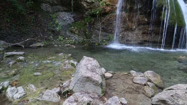 Jum Jum waterfall in the forest on a green background on a bright sunny day. Flora nature plants sights of Russia.