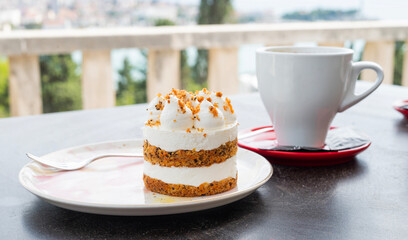 A delicious cream cake dessert served at a restaurant on a summer terrace with a cup of cappuccino coffee
