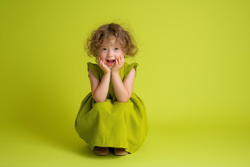 Happy young girl smiling and sitting on green  chartreuse color trend background