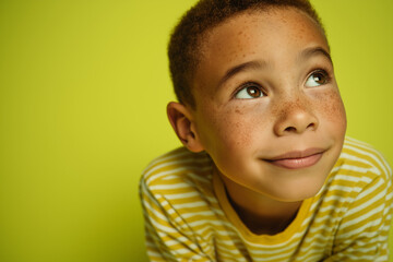 Young boy looking up with a smile against bright green background   with empty space for text