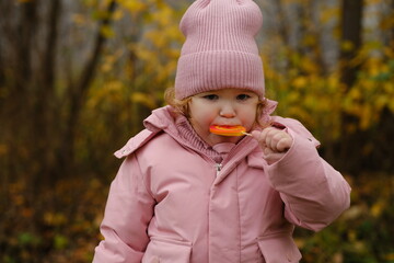 Young Child Enjoying a Lollipop While Exploring a Colorful Autumn Forest