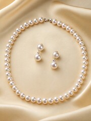 Obraz premium Elegant white pearl necklace and matching earrings displayed on smooth beige satin fabric, showcasing timeless luxury and refined fashion style