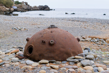 Rusted Sea Mine on Rocky Beach by the Sea