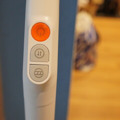 Close-up of the control panel of a white vacuum cleaner, featuring power and mode buttons