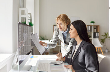 Portrait of young confident business women employees sitting at the desk on workplace, looking at...