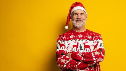 Fototapeta premium Merry satisfied smiling mature man wear knitted christmas sweater Santa hat posing on isolated yellow background