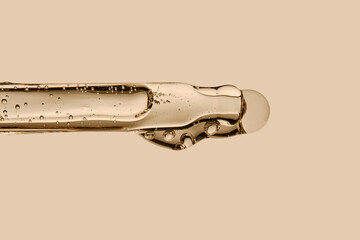 Serum in a pipette close-up on a beige background.