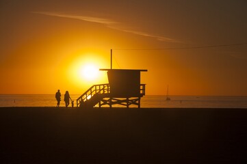 Naklejka premium Family by a Lifeguard House at Sunset