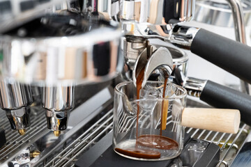 Coffee machine brewing espresso in to glass cup.Barista while preparing and working with coffee machine and making espresso coffee from arabica coffee beans.
