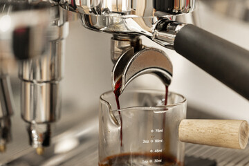 Coffee machine brewing espresso in to glass cup.Barista while preparing and working with coffee machine and making espresso coffee from arabica coffee beans.