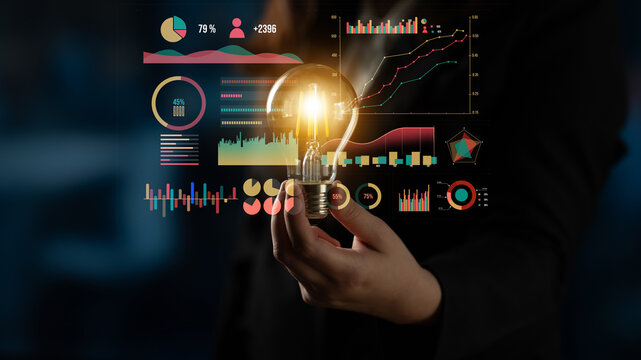 A business person creatively holds a glowing light bulb surrounded by colorful graphs and charts. The image symbolizes innovation, data analysis, and financial insights for modern business. Impute - Powered by Adobe