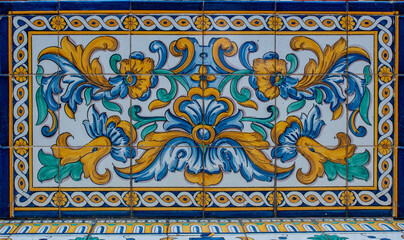 Background with Talavera ceramic panel with flowers and leaves in green, yellow, and blue