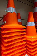 Stacked orange traffic cones arranged neatly in a storage area ready for use in road safety and...