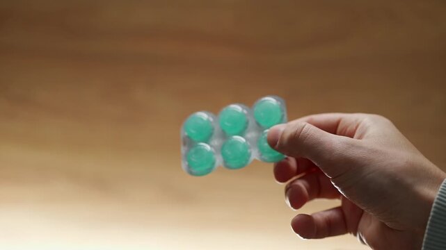 A person holding a blister pack of mint throat lozenges.
Menthol lozenges or tablets.
Sore throat relief and prevention during a sore throat.