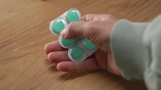 A person holding a blister pack of mint throat lozenges.
Menthol lozenges or tablets.
Sore throat relief and prevention during a sore throat.