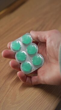 A person holding a blister pack of mint throat lozenges.
Menthol lozenges or tablets.
Sore throat relief and prevention during a sore throat.