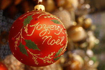 Boule de noël de couleur rouge et or ronde portant l'inscription joyeux noël et des incrustations...