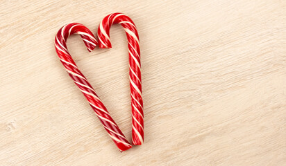 Heart made from Christmas candy canes on a wooden background