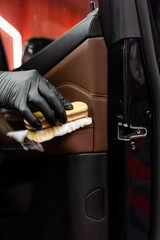 Detailing process includes brushing and washing car door panel to remove dust dirt and debris safely. Removing dust and dirt from car door panel using brush and detergent for deep clean.