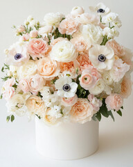 Luxurious pastel flower arrangement in a round white box, featuring cream roses, anemones, and ranunculus