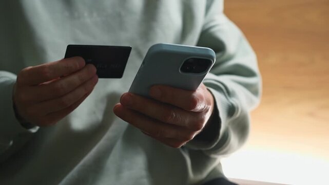 Money transfer from a bank card.
Transferring money to an e-wallet.
Topping up a mobile phone account and paying utility bills.
A person holding a phone and a credit card.