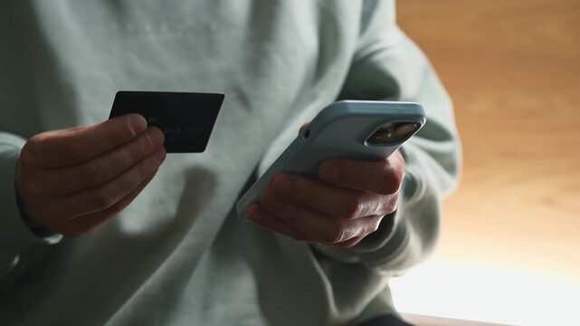 Money transfer from a bank card.
Transferring money to an e-wallet.
Topping up a mobile phone account and paying utility bills.
A person holding a phone and a credit card.