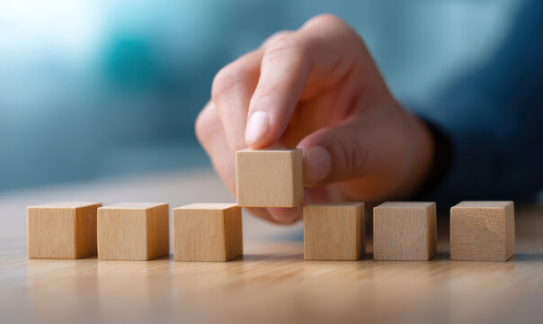 hand carefully selects one wooden cube from a row, symbolizing decision-making, strategy, or organization in a professional or planning context