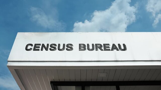 Census Bureau word sign clearly displayed on the official, professional facade of a government building beneath a crisp blue sky, signifying the authority for conducting population counts