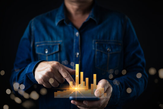 A businessman using a smartphone with a glowing holographic bar chart, representing business growth, data analytics, financial success, and digital marketing performance in modern technology.