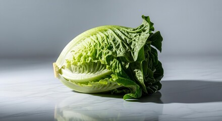 Obraz premium Fresh Romaine Lettuce Head on White Surface with Dramatic Lighting and Defined Shadows