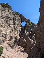 the bomb hole in the rock in the Bavella Mountains at sunshine und blue sky