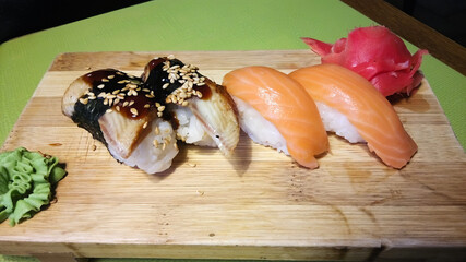 A plate of sushi with a piece of ginger on top.