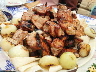 A plate of meat and onions. The meat is cooked and the onions are sliced.