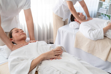 Obraz premium Caucasian couple customer enjoying relaxing anti-stress spa massage and pampering with beauty skin recreation leisure in day light ambient salon spa at luxury resort or hotel. Quiescent