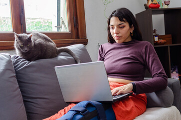 Young disabled woman using her laptop laying on the couch.