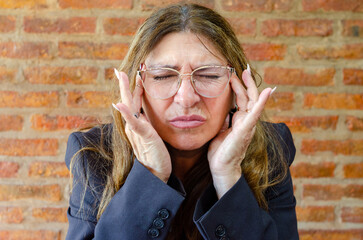 Mature female employee working from home feeling headache.