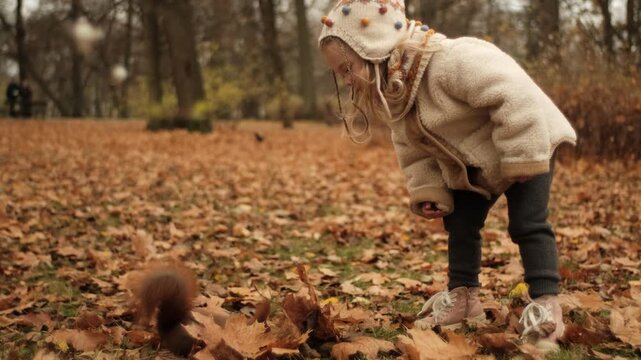 Close-up of a child squatting and feeding a squirrel