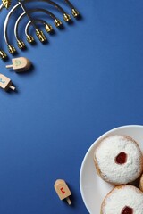 A festive vertical Hanukkah scene with a golden menorah, sufganiyot, dreidel set on a dark blue...