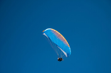 Oludeniz, Turkey. A paraglider pilot flies against a clear blue sky.
