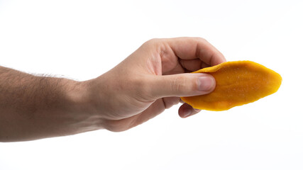 Hand holding a piece of bright orange mango slice against a light background