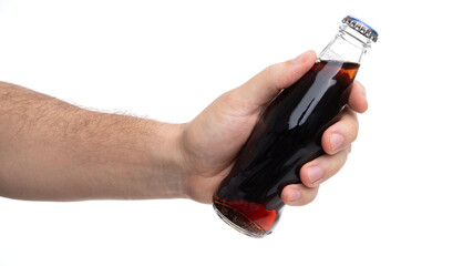Hand holding a glass bottle filled with dark soda against a plain background