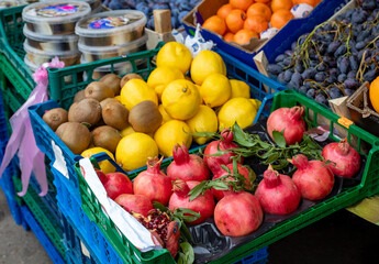 Pomegranates, lemons, kiwis, and grapes on display at a street market. Street vendors sell their fruits