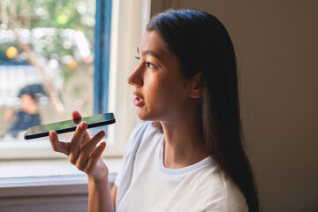 young Asian woman is interacting with artificial intelligence software by talking to her smartphone