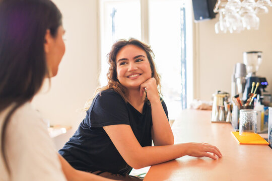 Young women enjoying conversation with girlfriend at a bar