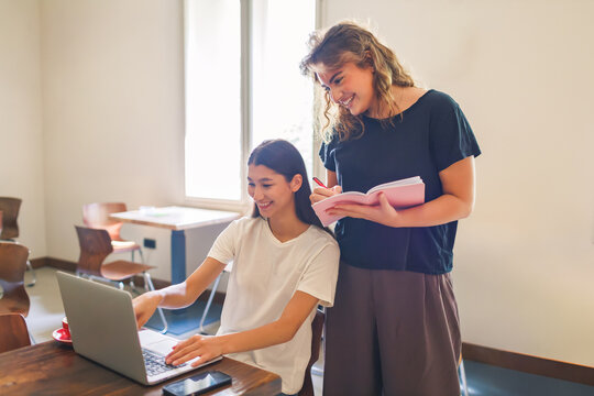 Two girlfriends enjoying a productive moment while working on laptops in a cozy cafe together