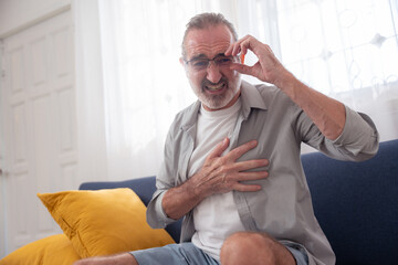 Elderly man clutching his chest in pain, indicating possible heart attack, chest pain, or cardiac...